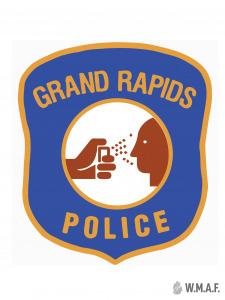 Mock Grand Rapids Police Department badge where the logo is a cop pepper-spraying a person's face.